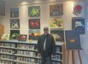 Photo of the artist in front of several paintings