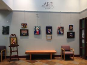 Photo of several paintings arranged on the art wall at the Rensselaer Library