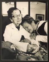 Photo of a young woman holding her seated grandmother.