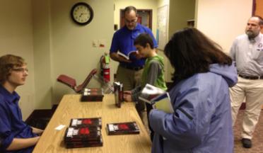 Photo of Logan Judy signing books after the program at the library.