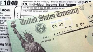 Photo of United States treasury check laid over 1040 federal tax return.