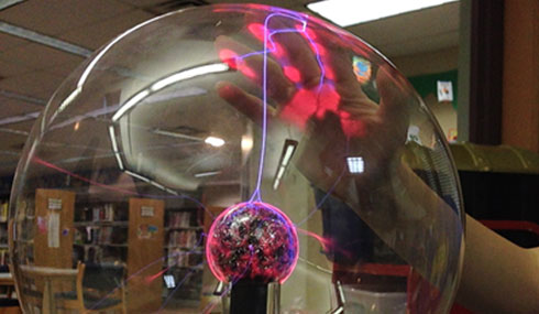 Photo of a hand illuminated by a plasma ball.