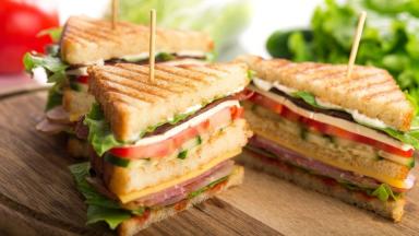Close up of grilled club sandwich triangles held together with skewers.