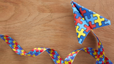 Photo of a paper airplane and tail, all covered with autism puzzle piece print.